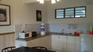 eine Küche mit einer Mikrowelle und einem Tisch mit Stühlen in der Unterkunft Genting Sempah Berjaya Hill Cottage in Bukittinggi