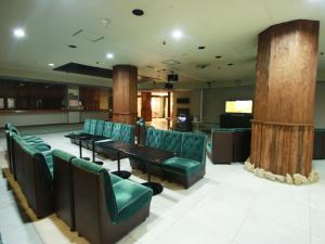 a waiting room with green chairs and tables and columns at Shimoda Itoen Hotel Hanamisaki in Shimoda