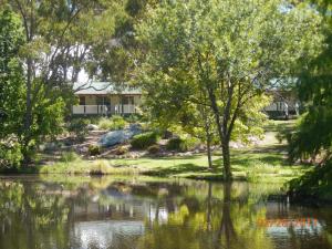 a view of a river with a house in the background at Granite Gardens Cottages & Lake Retreat in Stanthorpe