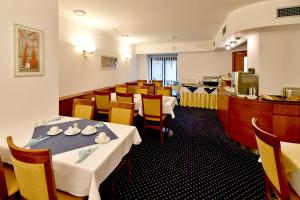 a restaurant with white tables and chairs and a counter at Hotel Coronet in Prague