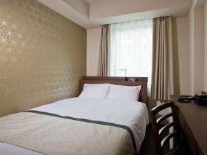 uma cama num quarto de hotel com uma janela em Tosei Hotel Cocone Kanda em Tóquio