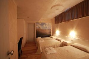 una camera con tre letti e un dipinto sul muro di I Rocchi Hotel a Tito