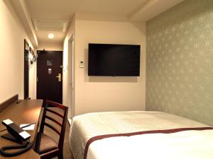 a hotel room with a bed and a television on the wall at Tosei Hotel Cocone Kanda in Tokyo