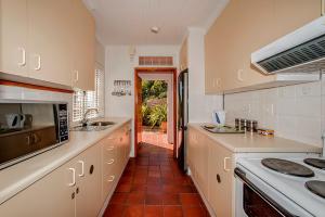 La cuisine est équipée de placards blancs et d'un four avec plaques de cuisson. dans l'établissement Salop House, à Fish Hoek