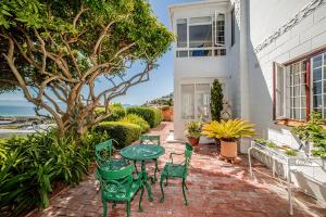 a patio with green chairs and a table and a tree at Salop House in Fish hoek