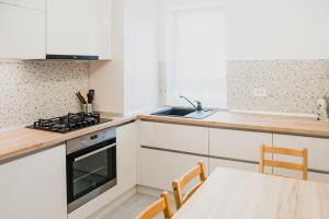 a kitchen with white cabinets and a table with chairs at Apartament 4Tourists in Braşov