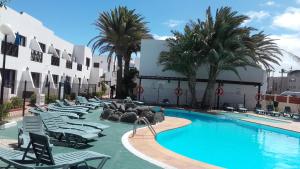 une piscine avec des chaises longues et un hôtel dans l'établissement Aloha Corralejo, à Corralejo