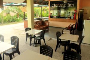 una sala da pranzo con tavoli e sedie in un ristorante di Chenang Inn a Pantai Cenang