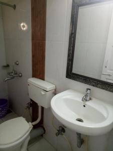 een badkamer met een wastafel, een toilet en een spiegel bij Sugar Plum Macedo Palms in Baga
