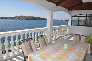 a table and chairs on a balcony with a view of the water at BM Apartments Rogoznica in Rogoznica