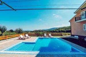 a swimming pool with chairs and a house at Villa Zen Imotski in Zmijavci