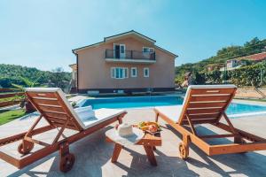 two wooden chairs sitting next to a swimming pool at Villa Zen Imotski in Zmijavci