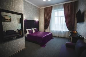 Habitación de hotel con cama morada y espejo. en Отель БЕССАРАБИЯ en Izmail