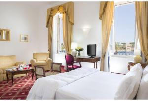 a hotel room with a bed and a desk and a tv at Grande Albergo Internazionale in Brindisi