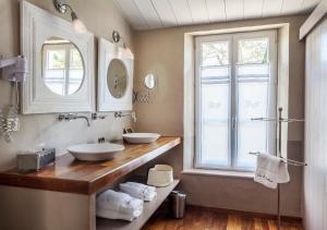 a bathroom with two sinks and a window at Hotel Les Bois Flottais in Le Bois-Plage-en-Ré