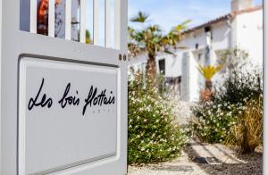 a white sign in front of a house at Hotel Les Bois Flottais in Le Bois-Plage-en-Ré