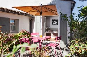 a pink table and chairs with an umbrella on a patio at Hotel Les Bois Flottais in Le Bois-Plage-en-Ré