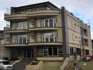 un gran edificio de apartamentos con balcón y coche en RL Veranda Suite, en Baguio
