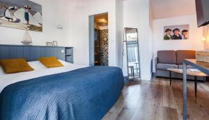 a bedroom with a bed and a couch and a chair at Hotel Les Bois Flottais in Le Bois-Plage-en-Ré
