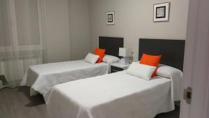 2 łóżka z pomarańczowymi poduszkami w pokoju w obiekcie San Anton Centro Apartment w mieście Logroño