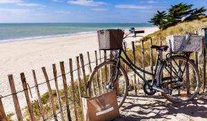 a bike parked next to a fence at the beach at Hotel Les Bois Flottais in Le Bois-Plage-en-Ré