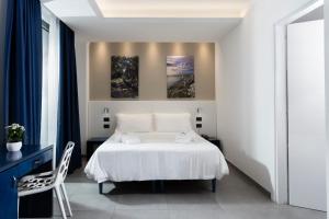 a bedroom with a white bed and two paintings on the wall at Hotel Belvedere in Torre dell'Orso