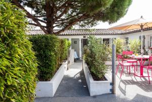 a patio with a table and chairs and a tree at Hotel Les Bois Flottais in Le Bois-Plage-en-Ré