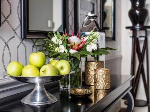 eine Schale mit Äpfeln auf einem Tisch mit einer Blumenvase in der Unterkunft La Malandrina - Apartments & Suites in Taormina