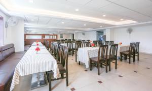 Treebo Trend Akshaya Mahal Inn في ميسور: غرفة طعام بها طاولات وكراسي طويلة