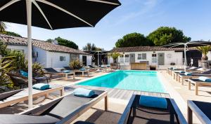 a swimming pool with lounge chairs and an umbrella at Hotel Les Bois Flottais in Le Bois-Plage-en-Ré