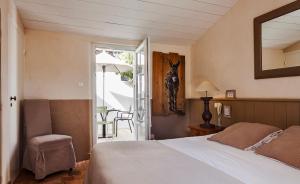 a bedroom with a bed and a table with a chair at Hotel Les Bois Flottais in Le Bois-Plage-en-Ré