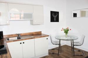 uma cozinha com armários brancos e uma mesa com flores em Princes Dock Chambers 3 em Hull