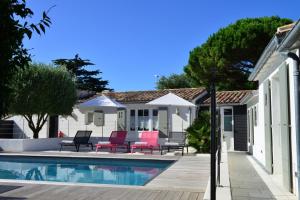 a house with a swimming pool in a yard at Hotel Les Bois Flottais in Le Bois-Plage-en-Ré