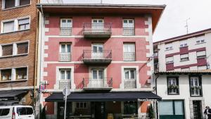 czerwony budynek z balkonami przy ulicy miejskiej w obiekcie Hotel Piñupe w mieście Lekeitio