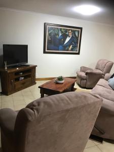 een woonkamer met 2 banken en een flatscreen-tv bij SA house in Modbury
