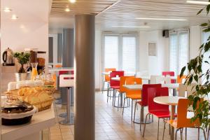 レ・ジュリスにあるPremiere Classe Les Ulis - Courtaboeufのカラフルな椅子とテーブルのあるカフェテリア