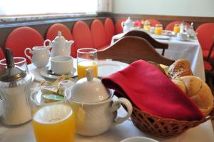 a table with a basket of bread and cups of orange juice at Gästehaus Hofer in Gumpoldskirchen