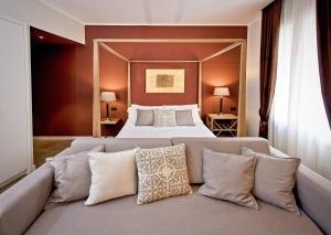 a bedroom with a bed and a couch with pillows at Delle Vittorie Luxury Rooms&Suites in Palermo