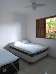 two beds in a room with a window at Vivenda Cravo&Canela in Abraão