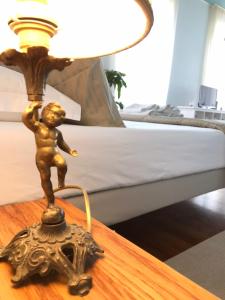 a small bronze lamp on a table next to a bed at Pep's Rooms by the sea in Trieste