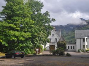 a black car parked in front of a white house at The Old Stables, Alltshellach Cottages in North Ballachulish
