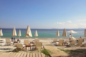 einen Strand mit Liegestühlen und Sonnenschirmen und dem Meer in der Unterkunft Barbati Bay Elegant Beach Apartments by Hotelius in Barbati