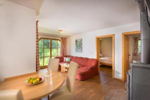 a living room with a red couch and a table at Hacklgut in Radstadt +9 photos
