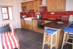 cocina con armarios de madera y encimera negra en Aran Thatch Cottage en Inis Mor