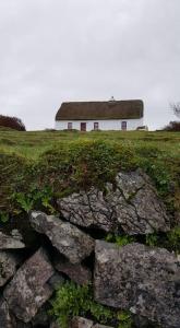 a house on top of a hill with a stone wall at Aran Thatch Cottage in Inis Mor