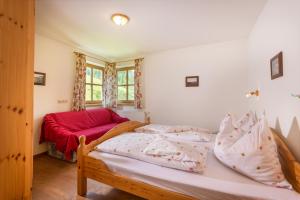 ein Schlafzimmer mit einem Bett und einem roten Sofa in der Unterkunft Hacklgut in Radstadt