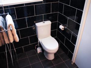 a bathroom with a toilet and black tiled walls at Mary House 46 in Porthcawl
