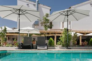 two chairs and umbrellas next to a swimming pool at Hotel Entreolivos in El Pedroso