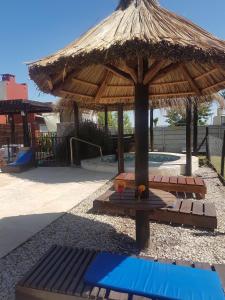 a pavilion with a table and a straw umbrella at las moraditas in Chascomús