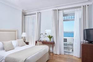 a bedroom with a bed and a window with a view of the ocean at Poseidonion Grand Hotel in Spetses